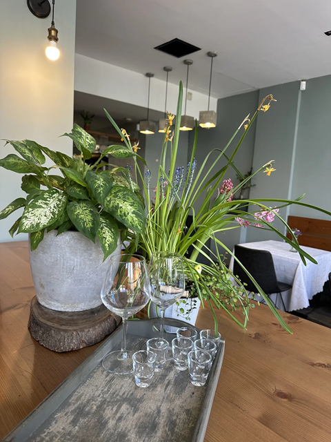 Table at Cookaki with wine glasses, fresh plants and Greek hospitality, near the Acropolis