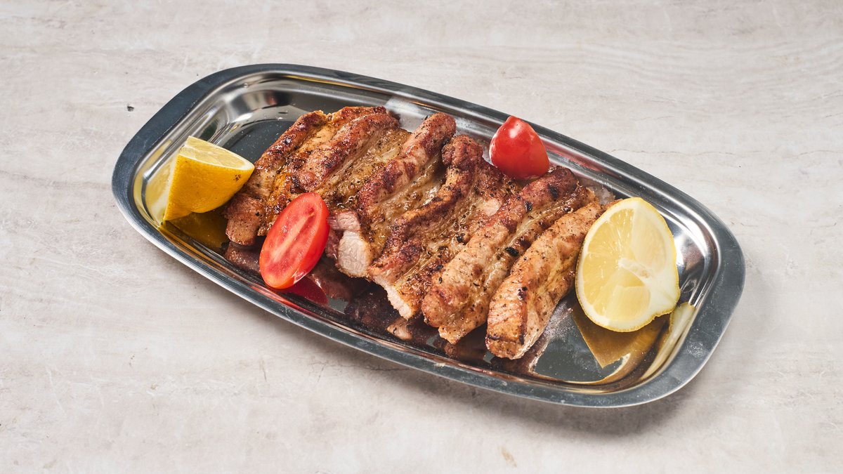 Char-grilled pansetakia pork belly slices with lemon and cherry tomatoes at Cookaki Athens