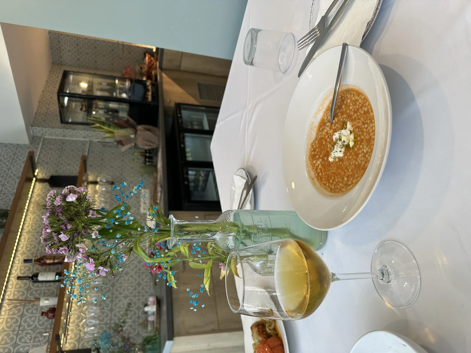 Trachanas tomato soup with crumbled feta and a glass of white wine at COOKaki Athens